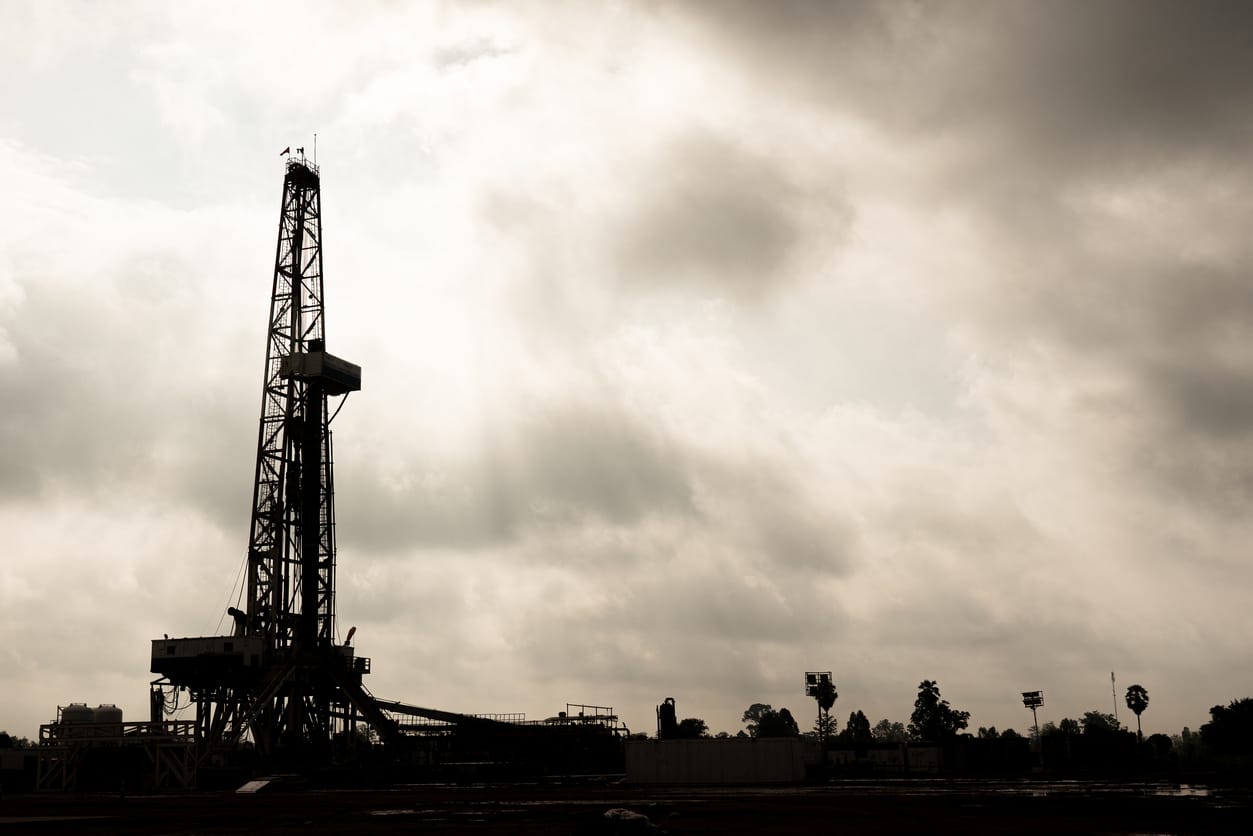 A drilling rig silhouetted under a cloudy sky