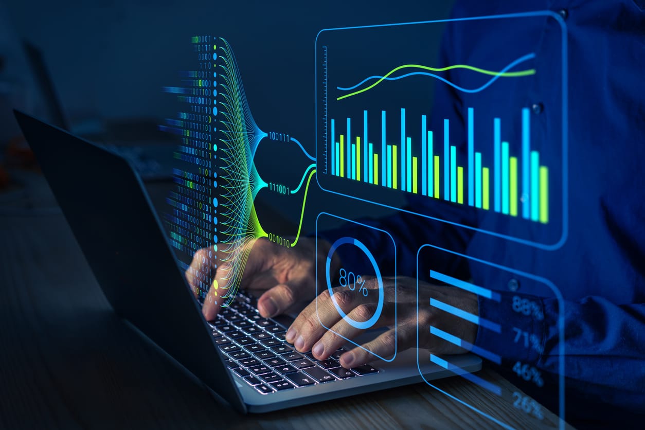 Hands on a laptop with digital charts and data visualizations overlaid